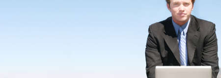 Business Man works on his laptop outside in the blue skyの写真素材