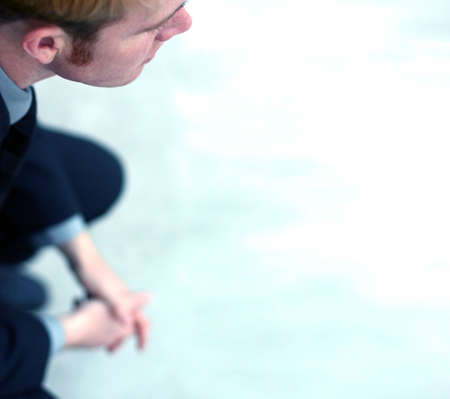 Business man sits and folds his hands in contemplation as he stares forwardの写真素材