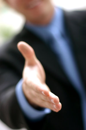 Business man in blue shirt and tie extends hand in a warm, open gesture