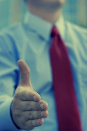 Businessman giving a handshake greeting with a red tie and blue shirtの写真素材