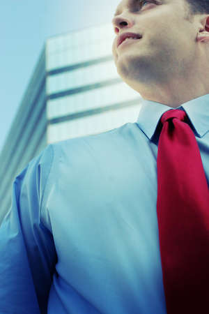 Businessman in front of a blue business building while he's wearing a red tieの写真素材