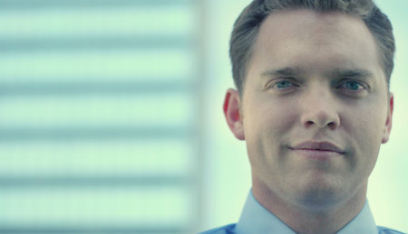 Businessman looking at the camera with a smile on his face standing in front of a blue business...