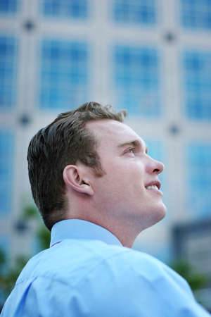 Businessman Stands with confidence and Looks Away with a blue button down shirt in front of a business buildingの写真素材