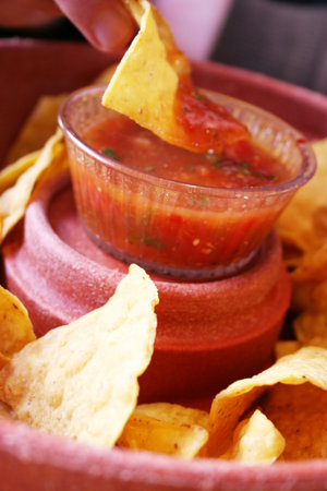 Chips and Salsa with someone dipping a chip in the salsa to eat itの写真素材