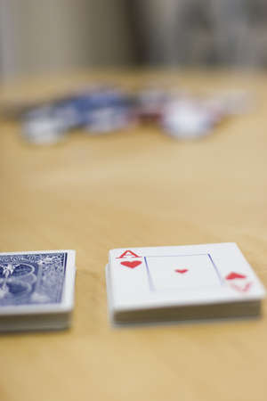 Deck of cards lying on a wooden table with the deck split and chips in the backgroundのeditorial素材