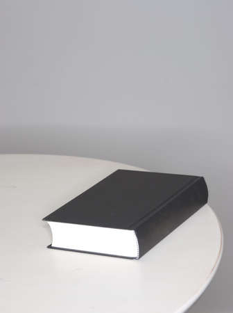 Large black book lying on the edge of a wooden tableの写真素材