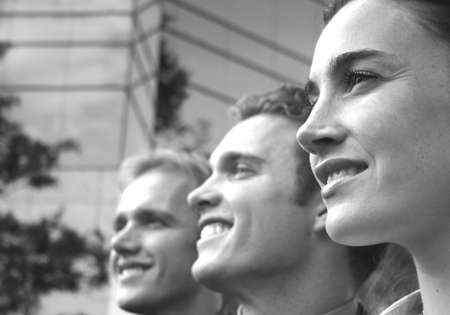 profile view of one female two males in a row looking away smiling in front of blue building structure の写真素材