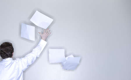 rear view of single man in white shirt raising his arm releasing stack of paperの写真素材