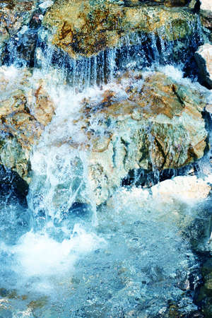 close-up view of water falling flowing over rocks into poolの写真素材