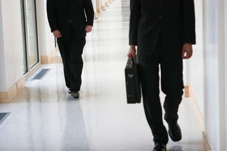 two businessmen walking in hallway の写真素材