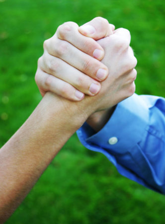 close up of two hands clasping with green grass in background