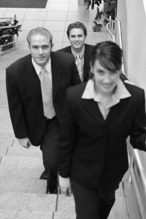three business people looking towards camera and walking up stairs 