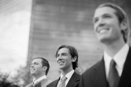 three business men standing and smiling in same directionの写真素材
