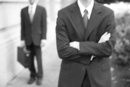 torso view of two businessmen standing in front of building with arms foldedの写真素材