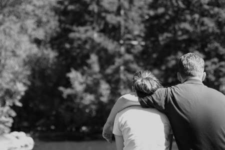 young man and young woman sitting down with man putting arm over woman's shouldersの写真素材