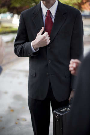 over shoulder view of businessman in suit standing holding briefcase and part of his jacketの写真素材
