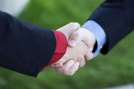 Two Businessmen seal their deal with a Handshake with green grass in the backgroundの写真素材
