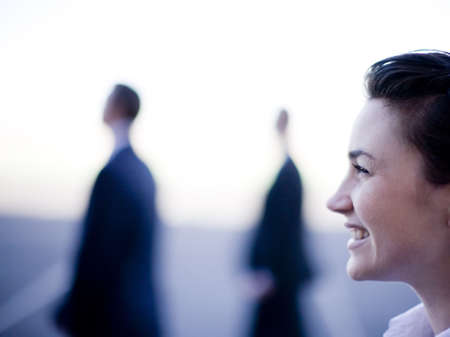 Three businesspeople standing together in a row looking in the same direction smilingの写真素材
