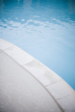 Blue swimming pool water next to gray edge of pool 