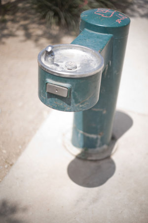 Dirty green drinking fountain in urban area