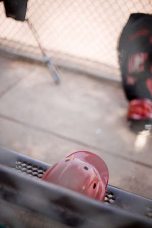 baseball helmet and bats sitting outside on a bench against the bench during a baseball gameの写真素材