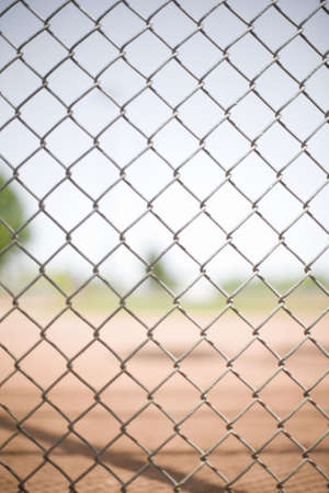 chain link fence pattern in front of a baseball field in the summerの写真素材