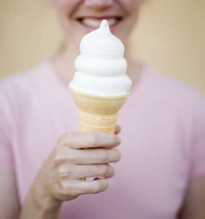 Young woman holding up ice cream cone - vanilla flavorの写真素材