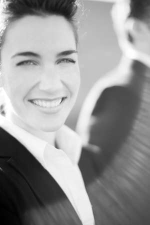 close view of attractive businesswoman standing wearing suit smiling with businessman standing next to herの写真素材