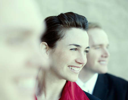 three businesspeople standing in a line with young attractive woman in the middle smilingの写真素材