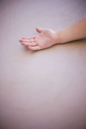 a young hand is laid across a tan background with the hand open and fingers outの写真素材
