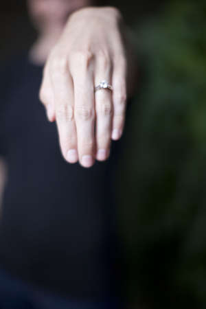 a woman holds her hand out and shows her diamond ring on her wedding fingerの写真素材
