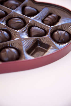 a big red box of chocolates in a heart shaped container with one of the chocolates missingの写真素材