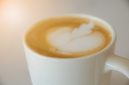 close up white coffee cup on white table with leaf image foamの写真素材