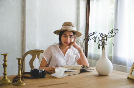 smiling asian women reading book on wooden tableの写真素材