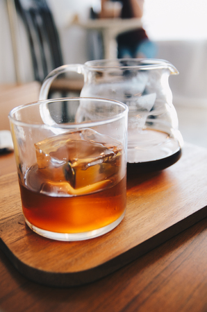 coffee drip in glass with cube ice on wooden plateの写真素材