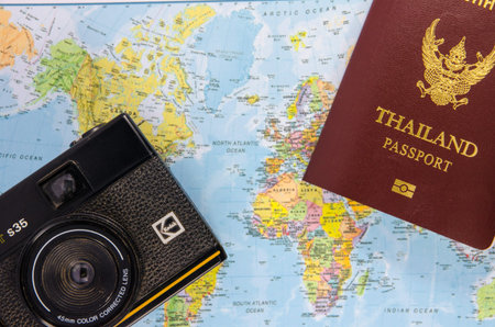 thai passport with film camera lay on world map