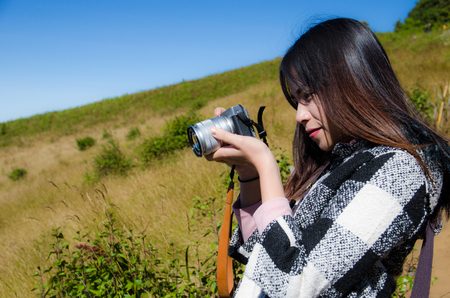 women traveller take a photo with digital camera on yellow grass backgroundの写真素材