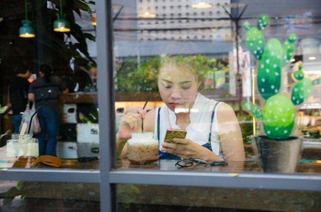 asian girl is looking smartphone in cafeの写真素材