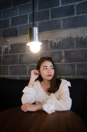 asian pretty girl sitting in cafe is looking somethingの写真素材