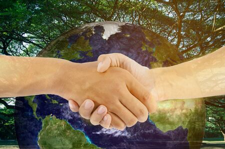 two man are hand shaking on earth and tree backgroundの写真素材