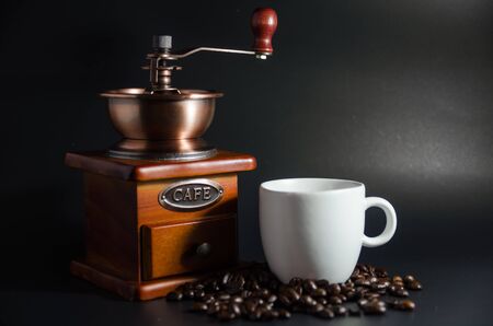 white coffee cup and coffee grinder and coffee beans on black backgroundの写真素材