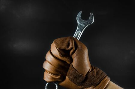 a wrench was holding by leather glove man hand in dark lightの写真素材