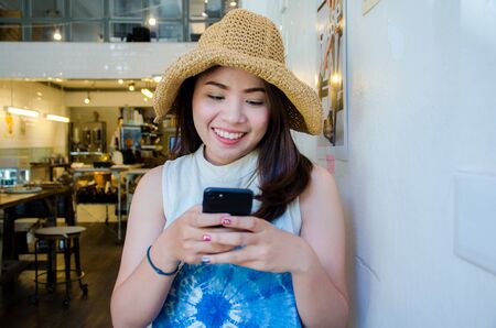 asian girl holding phone in coffee cafe with smile faceの写真素材