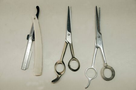 Scissors and razor blades on old white tableの写真素材