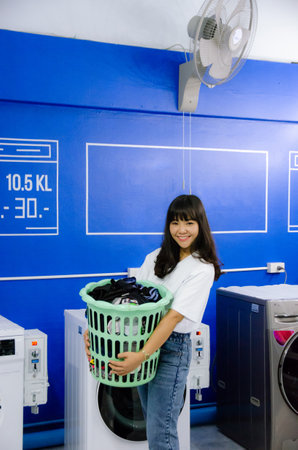 Asian girl is holding  basket in laundry shop with smile faceの写真素材
