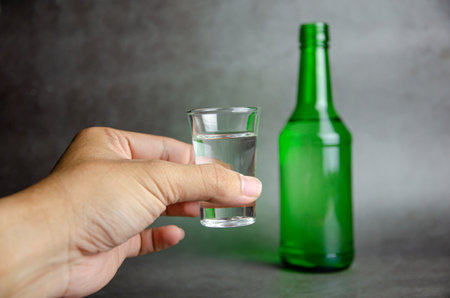 soju bottle on grey background with hand, selective focusの写真素材