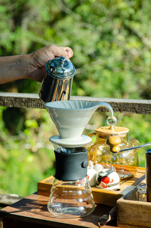 male hand is pouring coffee on ceramic dripper on green backgroundの写真素材