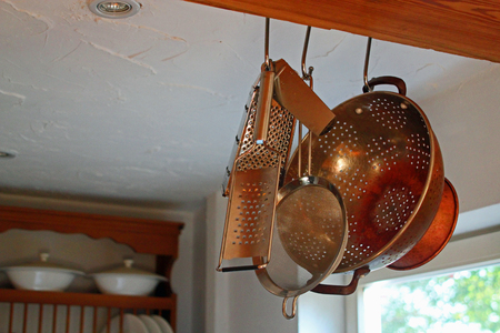 Country kitchen with close-up of kitchen utensils hanging from a beam with plate rack in the backgroundの写真素材