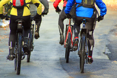 Four cyclists on mountain bikes wearing bright colors symbolizing speed, exercise and fitnessの写真素材