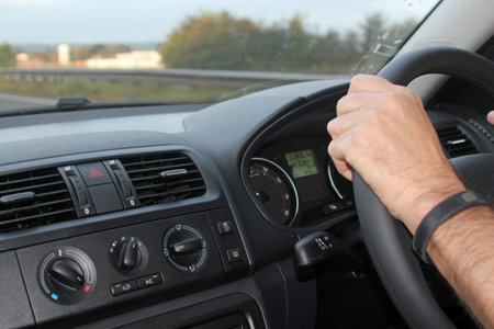 Close up of a car dashboard and a man's hands on the steering wheel symbolizing road safety, hands...